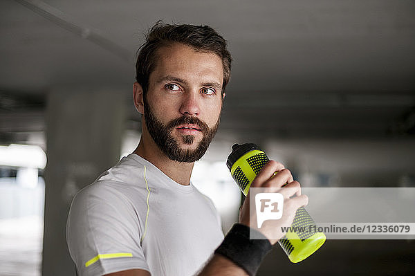 Athlete in parking garage holding drinking bottle