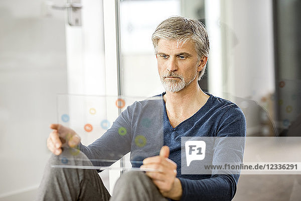Mature businessman using transparent touchscreen computer