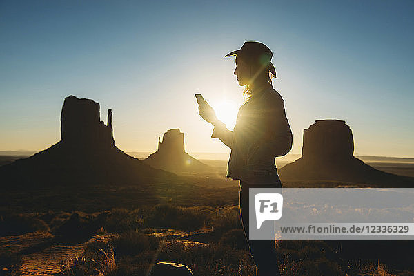 USA Utah Woman using mobile at sunrise in Monument Valley