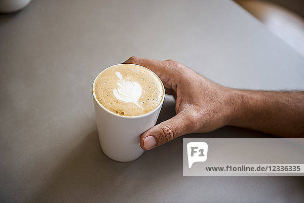 Hand and cup of cappuccino in a cafe