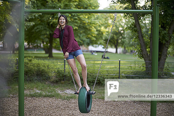 Laughing young woman having fun on a swing