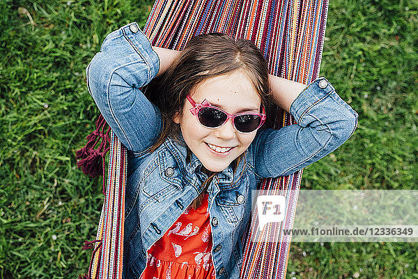 Portrait of smiling girl wearing sunglasses lying in hammock