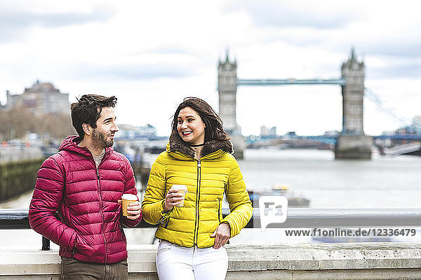 UK  London  couple with coffee to go standing on bridge over the Thames