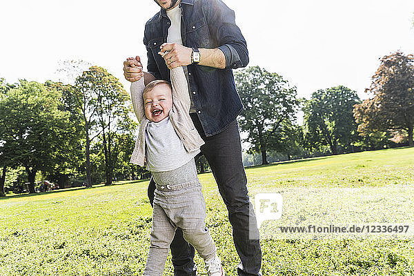Father holding hands of happy son in a park