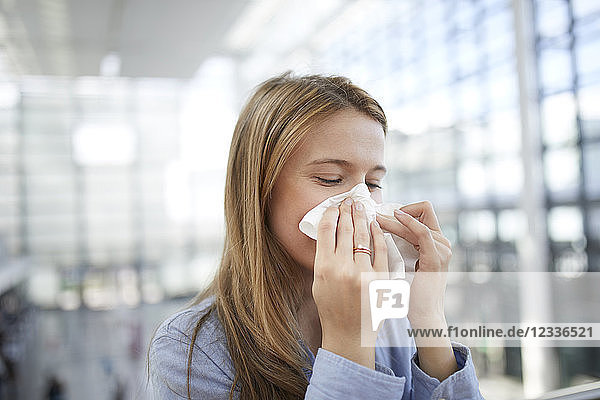 Young woman blowing nose