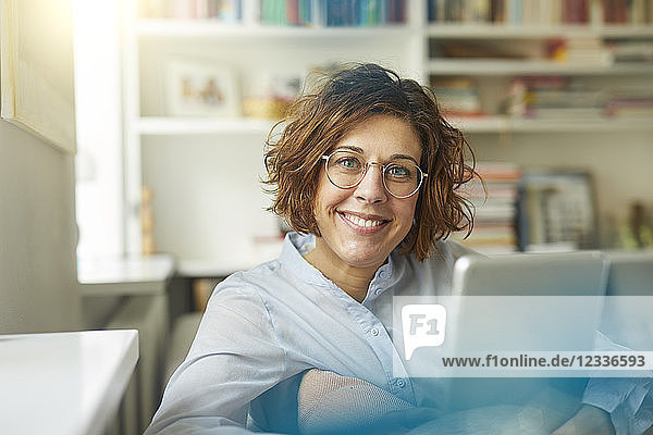 Portrait of content mature woman with tablet at home