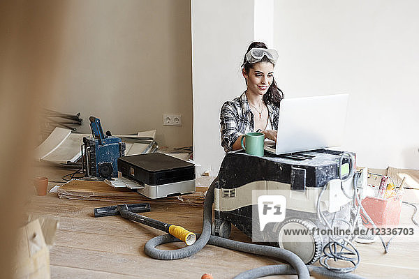 Young woman renovating her new flat  using laptop