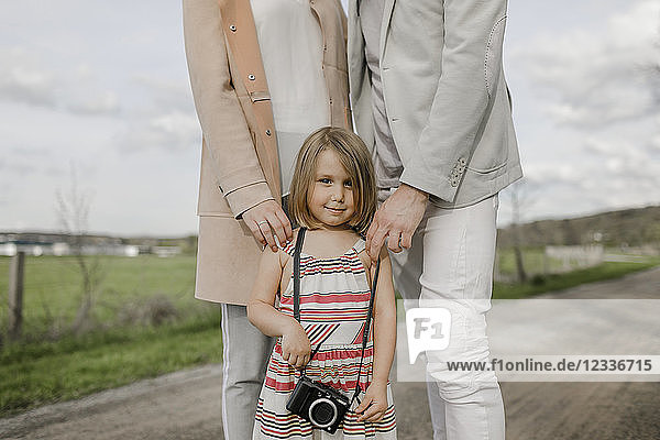 Portrait of smiling little girl with parents standing behind her