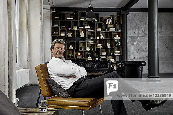 Portrait of mature man sitting on chair in loft