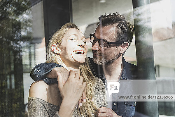 Happy mature couple behind windowpane at home