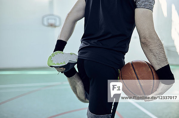 Man with basketball  stretching leg  indoor