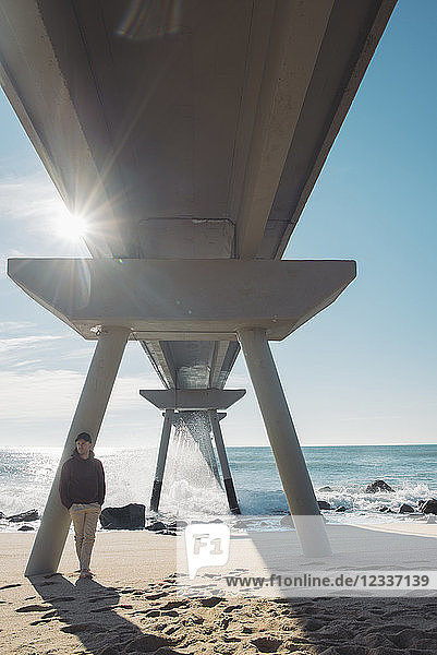 Man standing relaxed under bridge on the beach