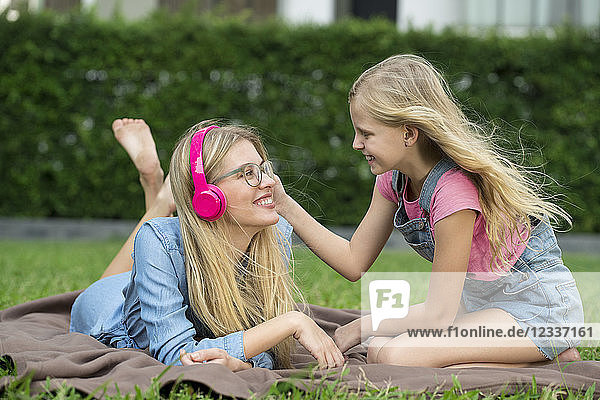 Happy mother and daughter listening to music together in garden