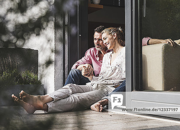 Content mature couple relaxing together at open terrace door