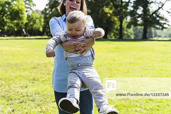Happy mother lifting up son in a park