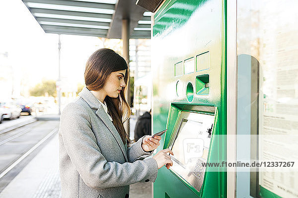 Spain  Barcelona  woman buying ticket from automated machine at station