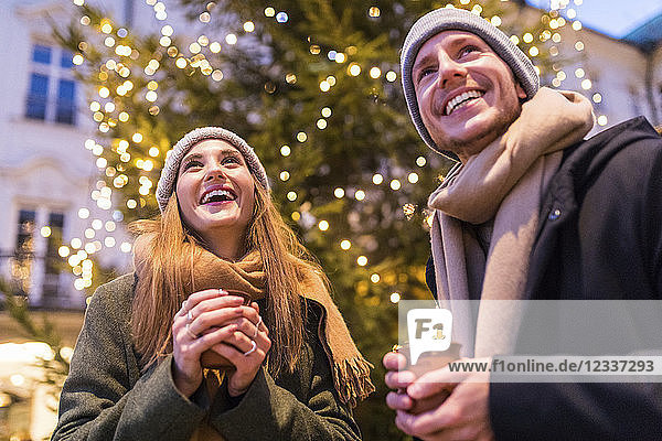 Laughing young couple drinking mulled wine at Christmas market
