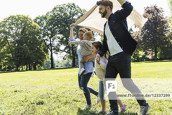 Happy family walking with a blanket in a park