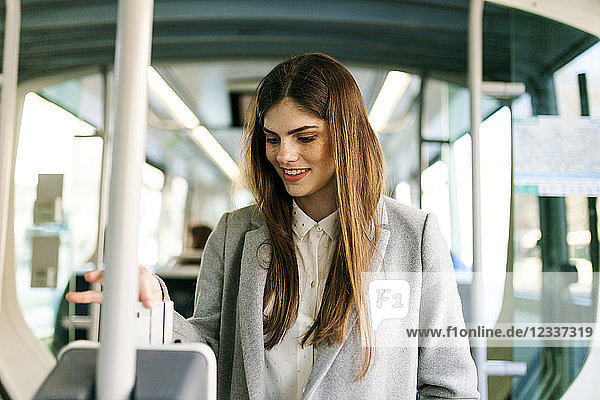 Portrait of smiling young woman validating ticket in tramway