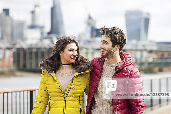 UK  London  young couple walking arm in arm on a bridge
