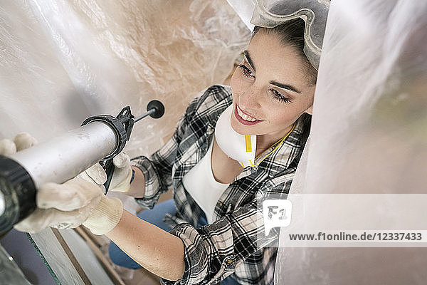Young woman renovating her new flat  using cartridge dispenser