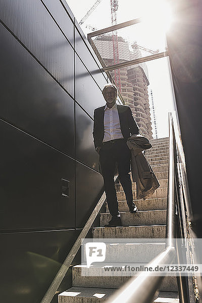 Mature businessman walking on staircase in the city