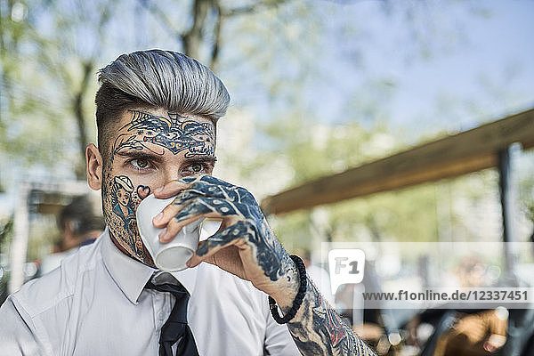 Young businessman with tattooed face  drinking coffee