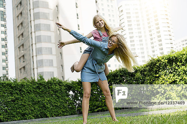 Happy mother and daughter having fun in urban city garden