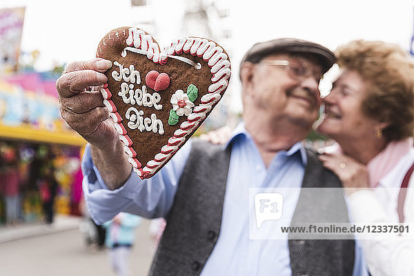 Hand of senior man holding ingerbread heart on fair close-up