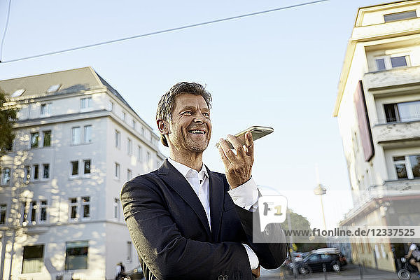 Smiling mature businessman using smartphone in the city