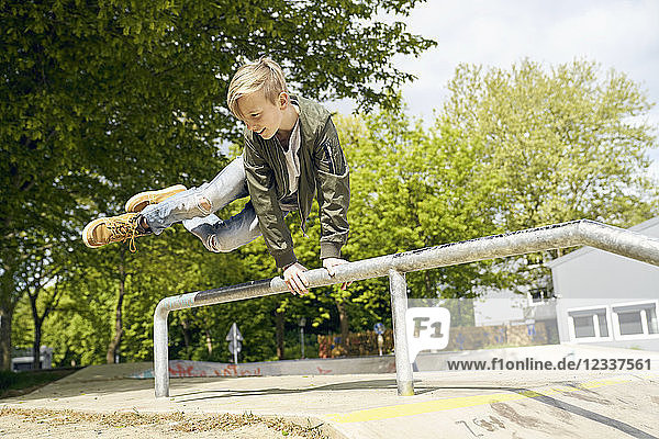Boy jumping over railing in skatepark