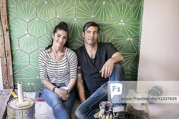 Couple renovating new house  sitting on ground taking a break
