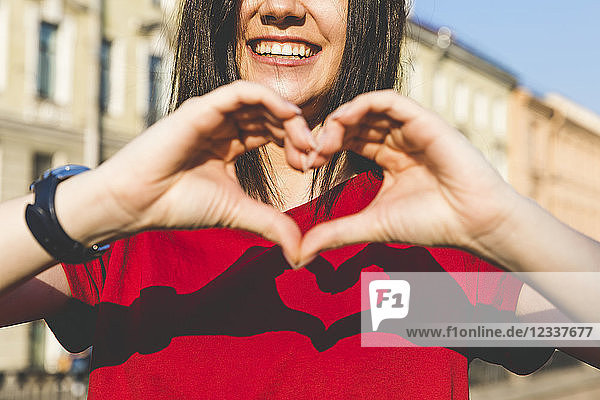 Woman's hands shaping heart  shadow on red t-shirt