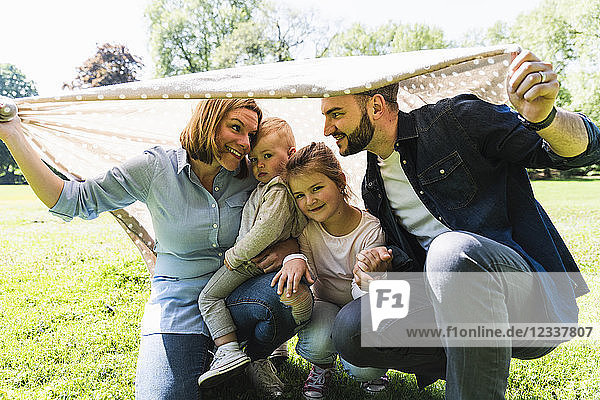 Happy family under a blanket in a park