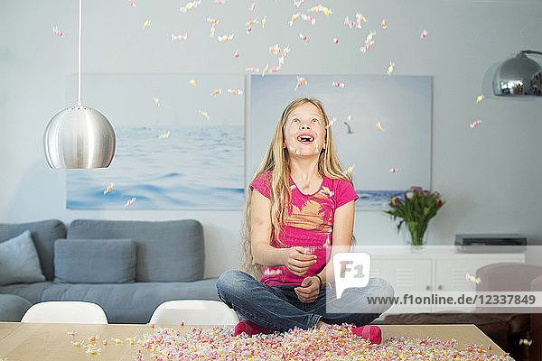 Girl sitting on table  candies falling down
