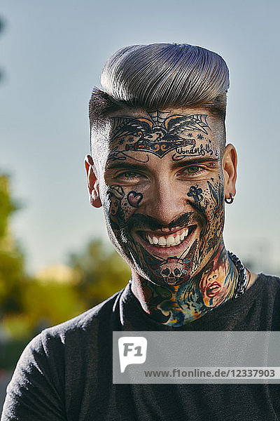 Portrait of smiling tattooed young man outdoors