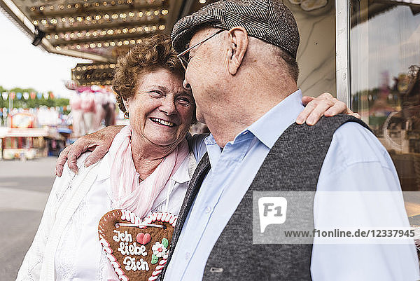 Happy senior couple with gingerbread heart on fair