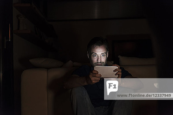 Man sitting in the dark at home starring at smartphone