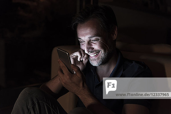 Portrait of happy mature man using cell phone at home