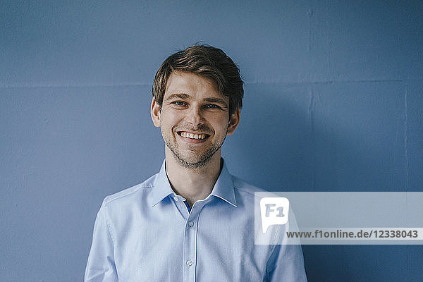 Portrait of smiling man in front of blue wall