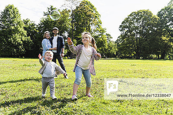 Happy family playing with soap bubble in a park