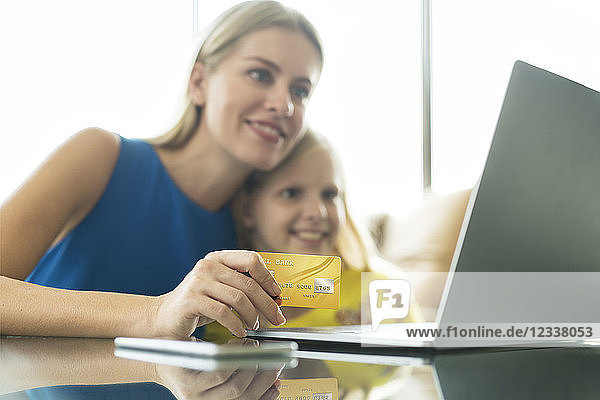 Mother and daughter using laptop and credit card together
