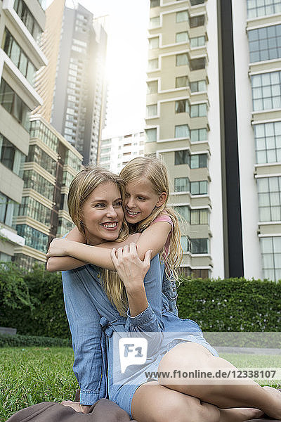 Happy mother and daughter hugging and smiling in urban city garden