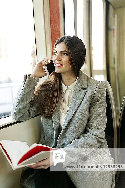 Portrait of smiling young woman on the phone in tramway