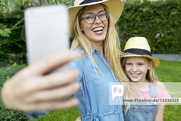 Happy mother and daughter taking a selfie in garden