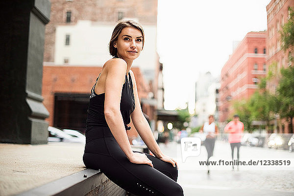 Portrait of woman sitting on wall looking at camera  New York  USA