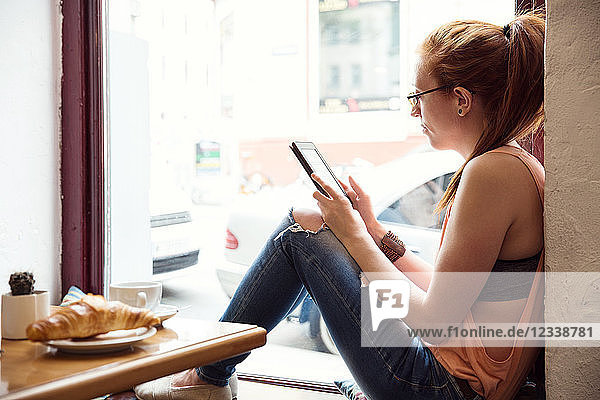Junge Frau benutzt Mobiltelefon im Café