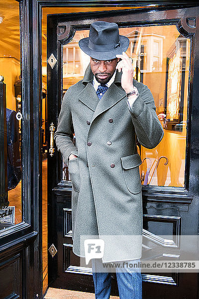 Cool male customer wearing trilby outside tailors shop  portrait