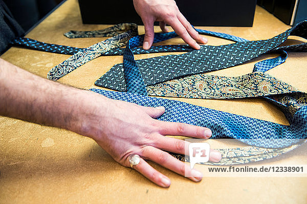 Kunde wählt eine Krawatte auf dem Tisch der Schneiderei  Detail der Hände