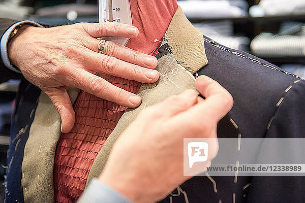 Tailor preparing bespoke suit jacket on tailors dummy  close up of hands